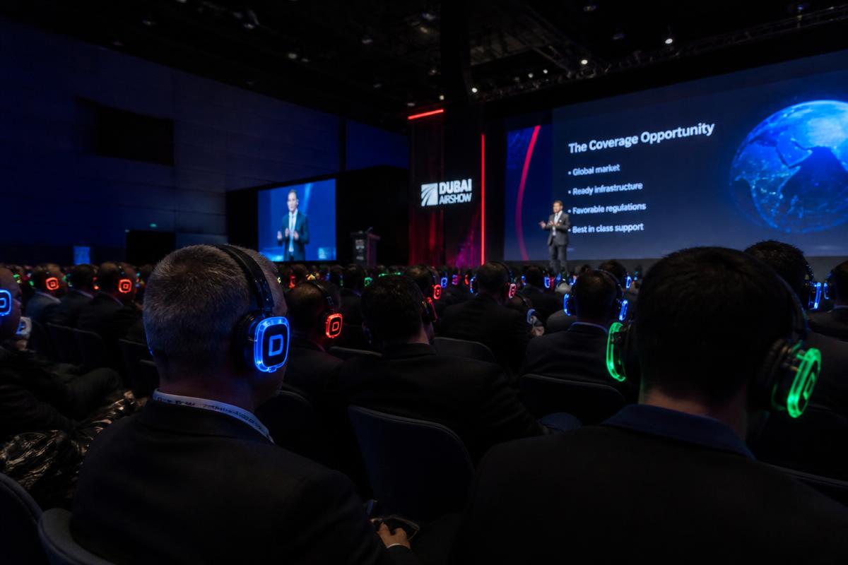 Delegates in a conference hall wearing wireless headphones with Arabic, English and French channel indicators